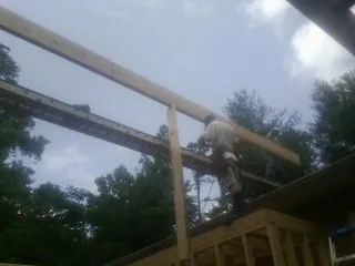 Carpenter setting a ridge beam over a new addition frame — Ice Dam Removal by Roofing Brothers in Binford
