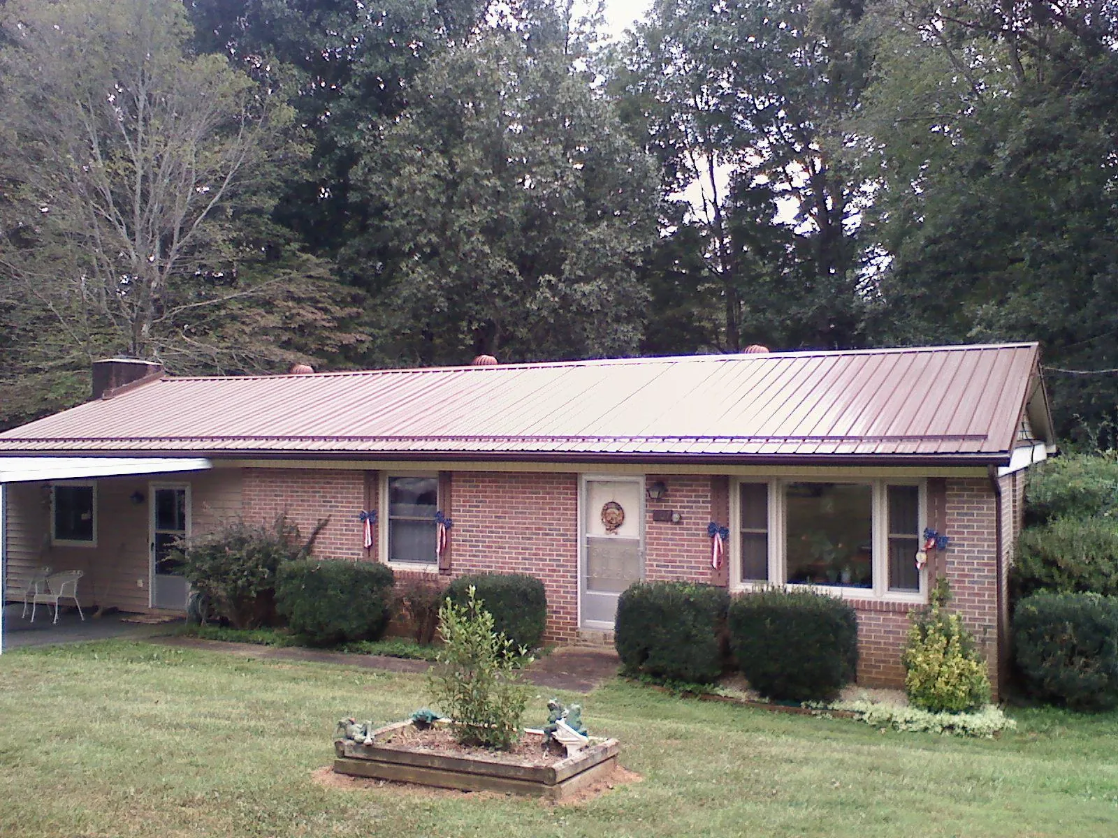 Bronze metal roof on a brick ranch home with a carport in Binford