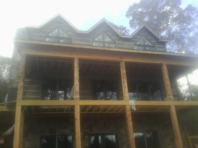 Dormers and porch framing on a large log home under construction — Roof Coating work by our crew in Binford