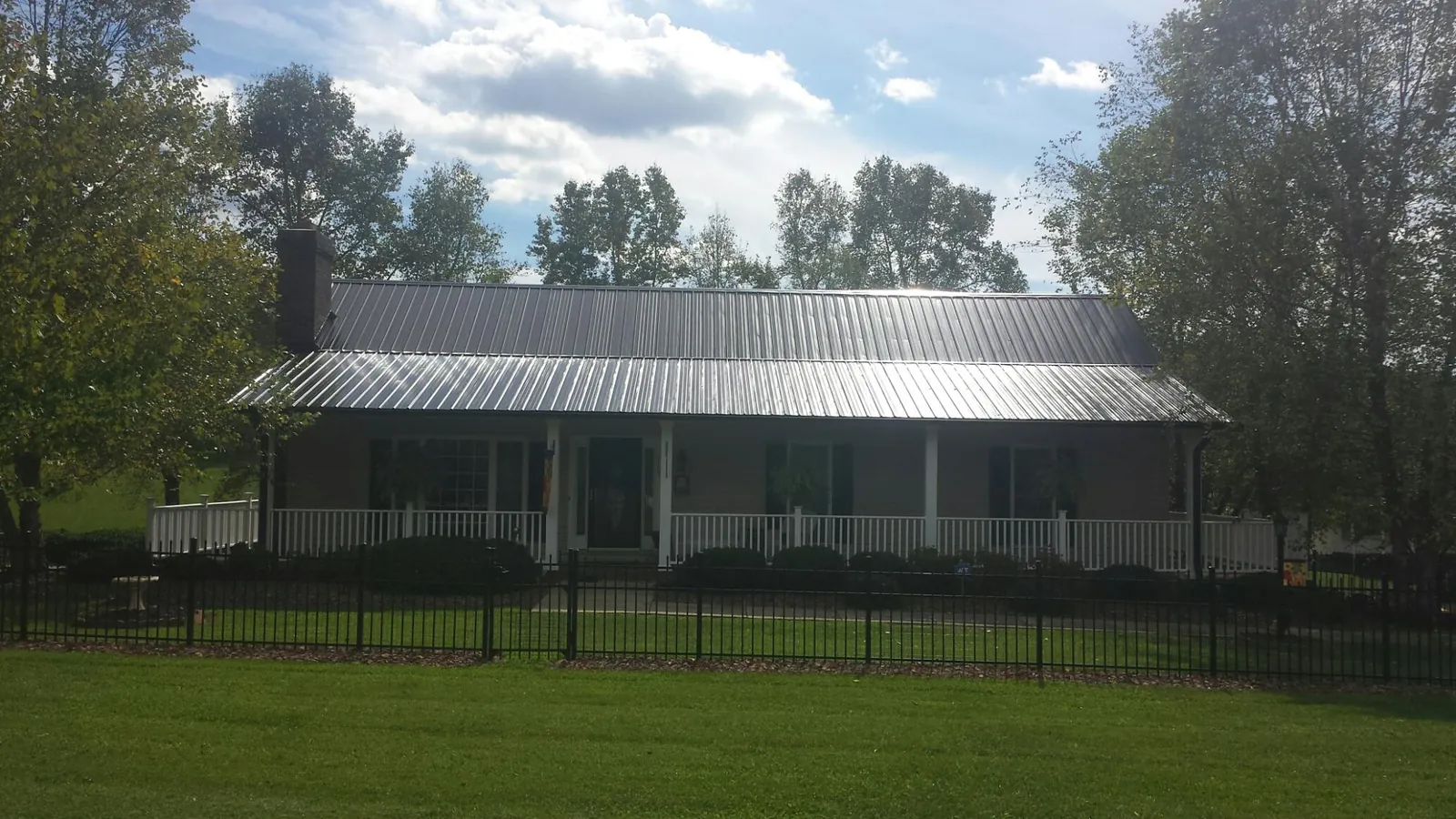 Gray metal roof on a brick ranch with a full width front porch — Gutter Guard Installation work by our crew in Binford