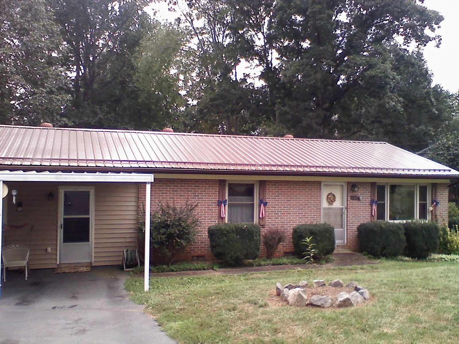 Bronze metal roof and carport on a brick ranch home — Roof Repair work by our crew in Binford