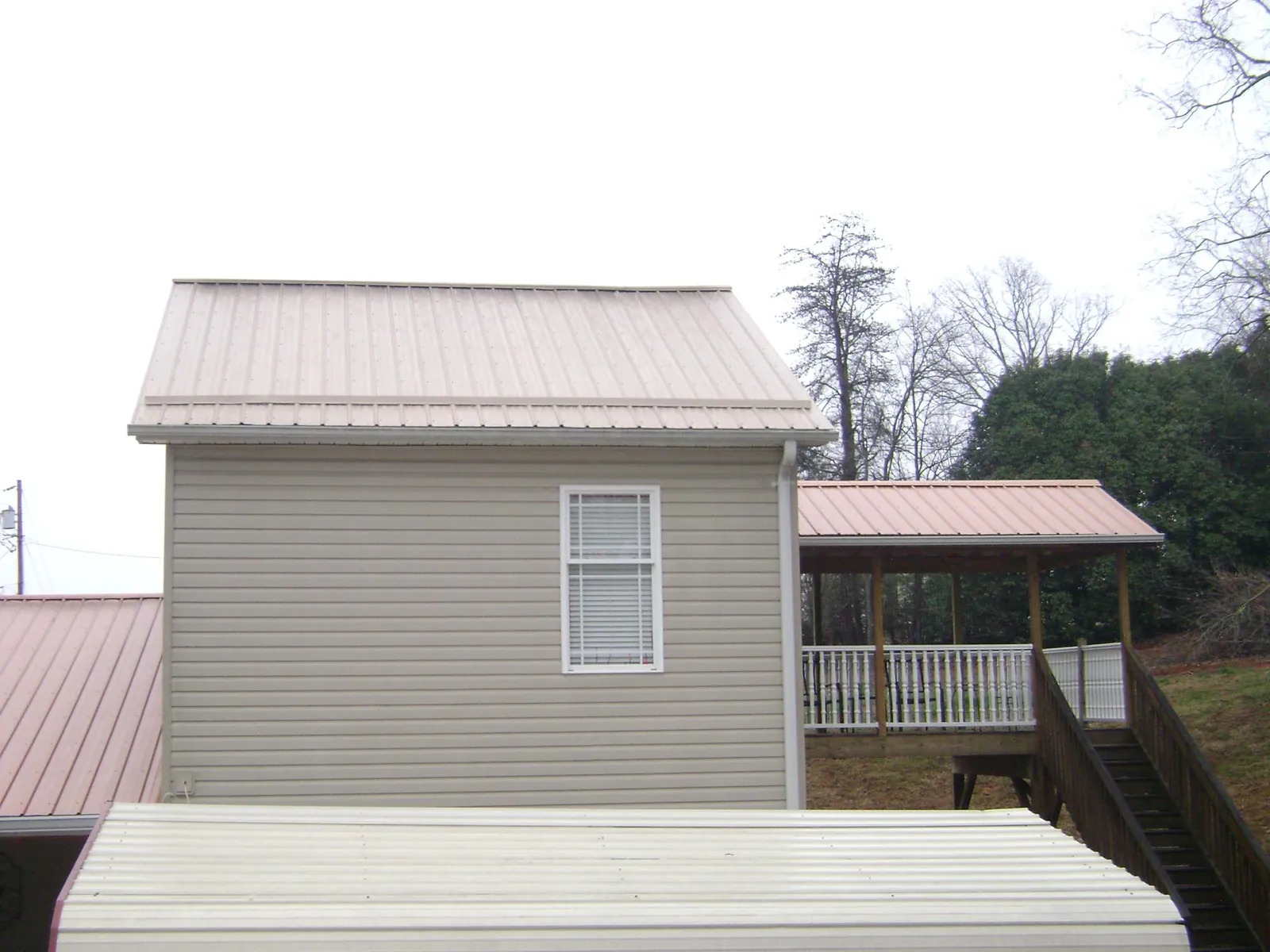 Tan metal roofs on a two story addition and attached porch, from a Roof Replacement job in Binford